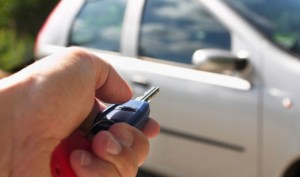 Close-up on a Hand Pointing a Car Key at a Parked Car